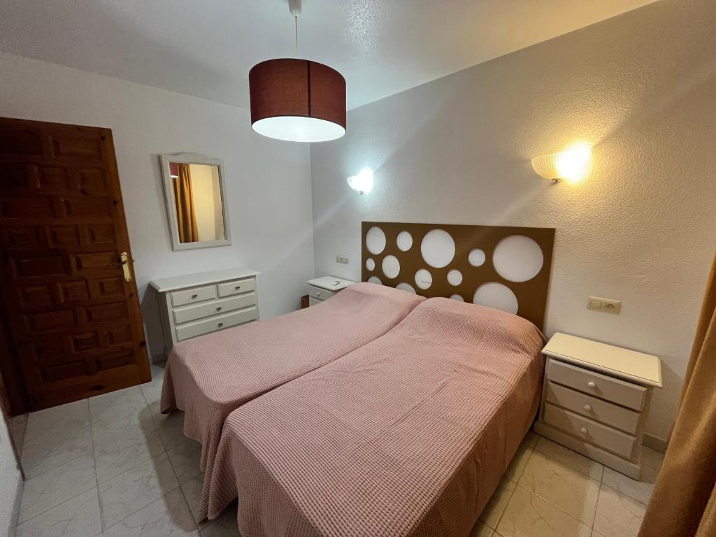 1 dormitorio con 1 cama grande con manta rosa en Luna Blanca Vera Playa, en Los Amarguillos