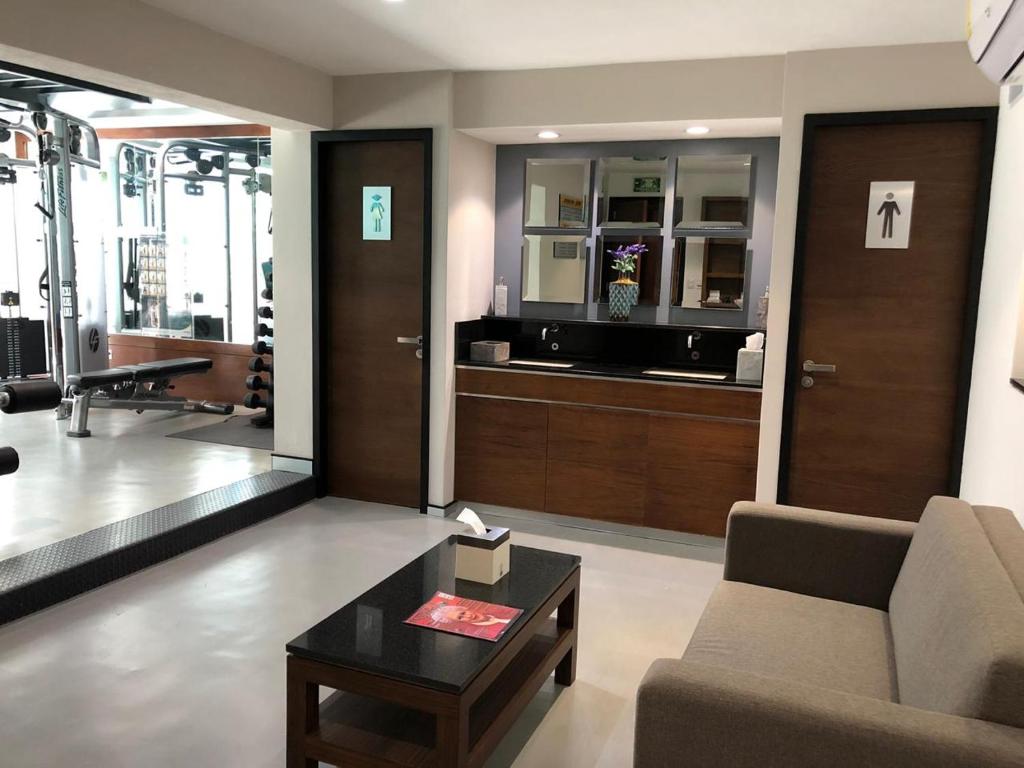 A small lounge beside a vanity area and the entrance to the fitness room.