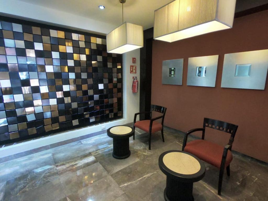 A decorative waiting nook with two chairs, small tables and pendant lighting.