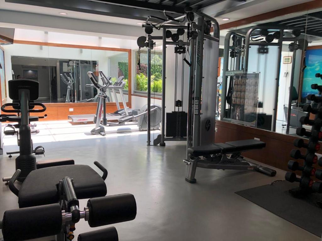 A bright hotel gym with cardio machines, a cable station, weights, and mirrors.