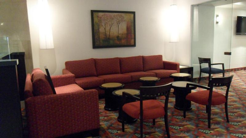 A lounge seating area with red sofas, armchairs and several low tables.