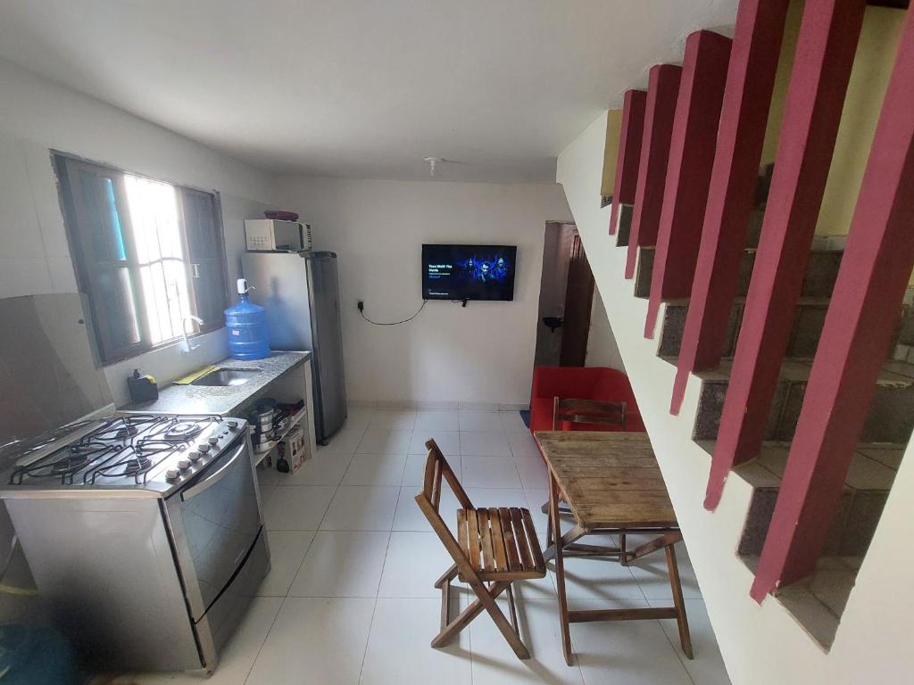 een kleine keuken met een fornuis en een tafel en stoelen bij Duplex econômico vila ponta negra in Natal