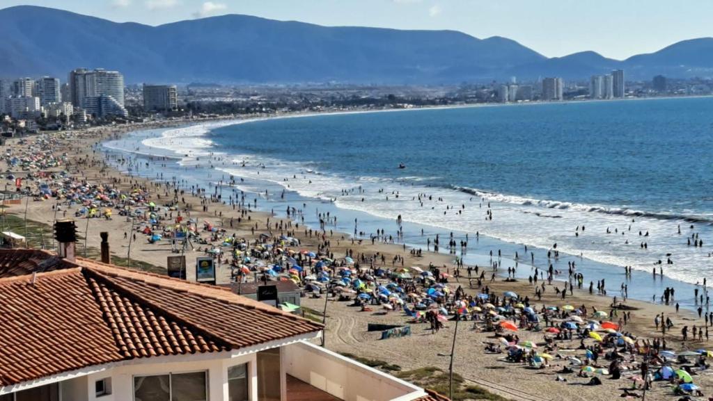 a crowd of people on a beach with the ocean at Depto Oceanic III La Serena in La Serena