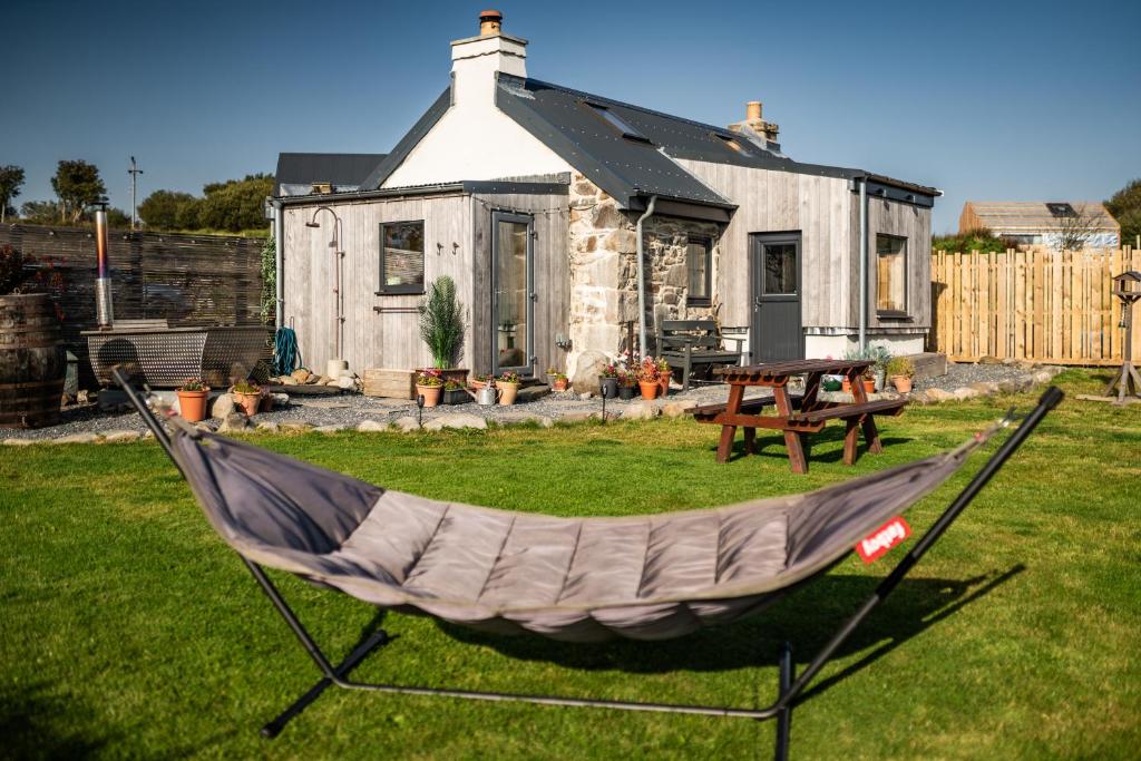 a hammock in a yard in front of a house at Jura, Mrs Leonard's Cottage in Isle of Jura