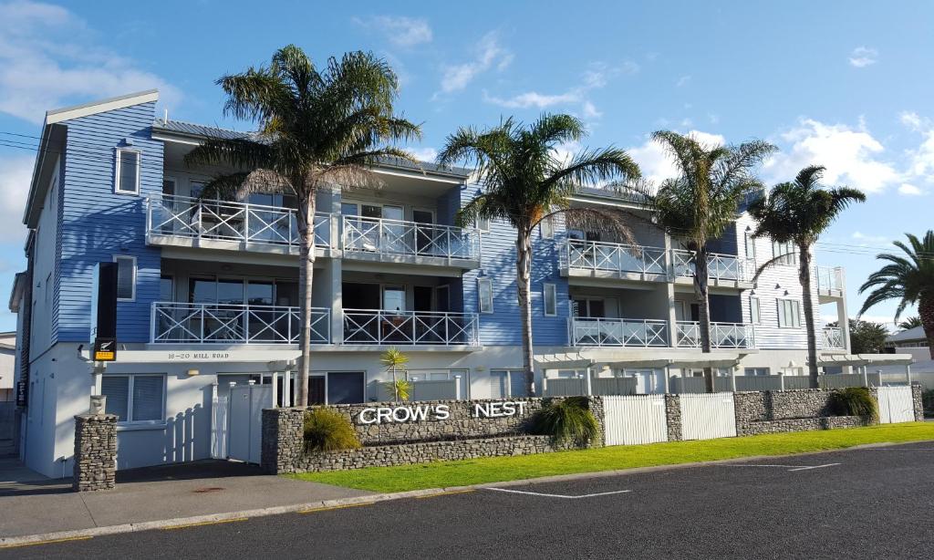 a blue building with palm trees in front of it at Crow's Nest Apartments in Whitianga