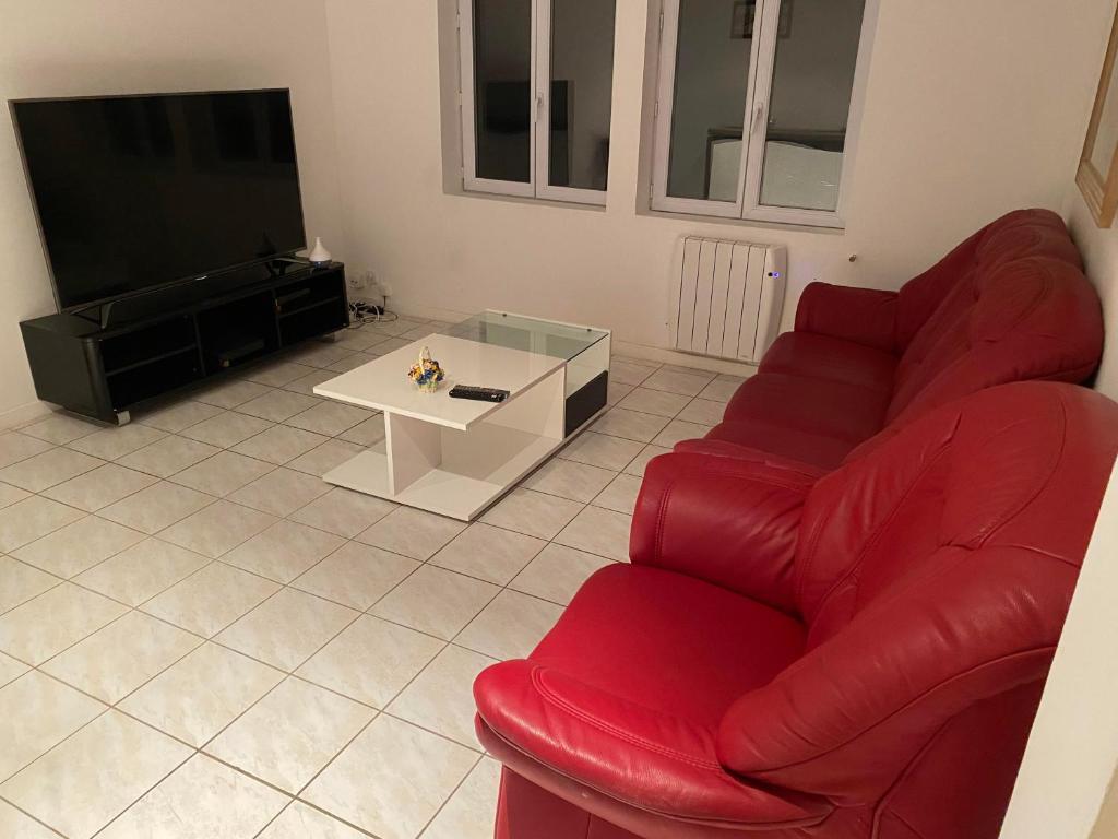 ein Wohnzimmer mit einem roten Sofa und einem TV in der Unterkunft Claude et Carole in Obenheim