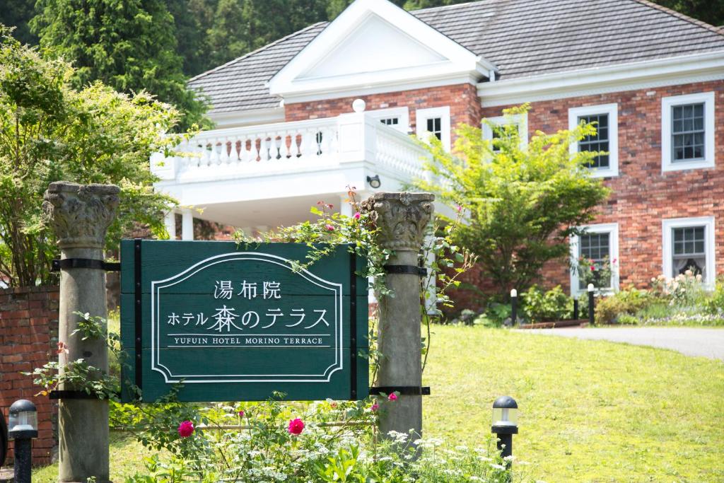 ein grünes Schild vor einem Backsteinhaus in der Unterkunft Yufuin Hotel Mori-no-Terrace in Yufu
