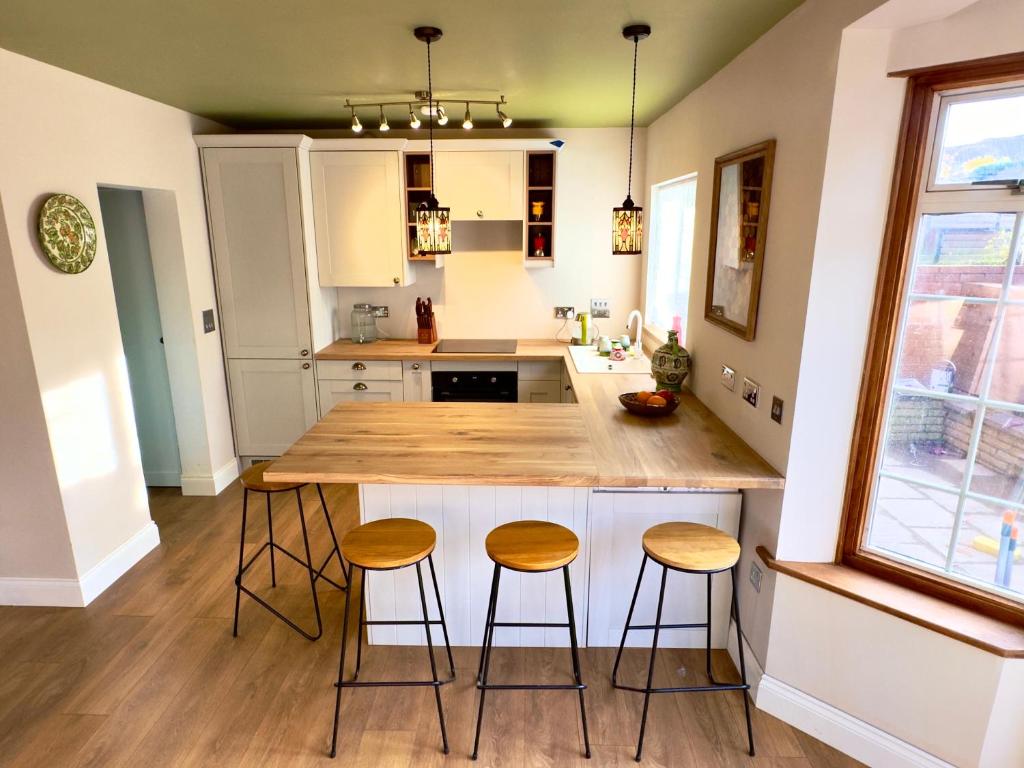 a kitchen with a large island with three stools at Beautiful House in London - Abbey Wood in Abbey Wood