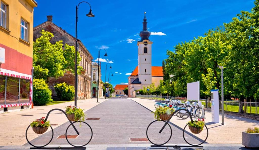 eine Gruppe von Fahrrädern, die auf einer Straße mit einer Kirche geparkt sind in der Unterkunft Prenoćište Skitnica Kapronca in Koprivnica