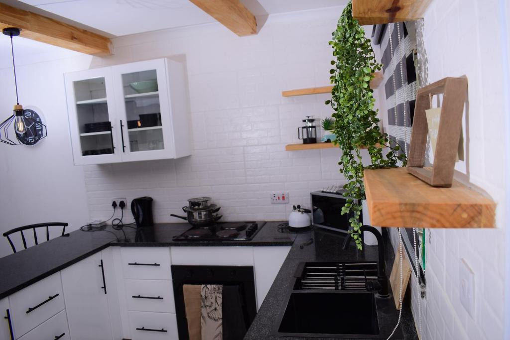 a kitchen with white cabinets and a black counter top at Kanana Villas in Otse