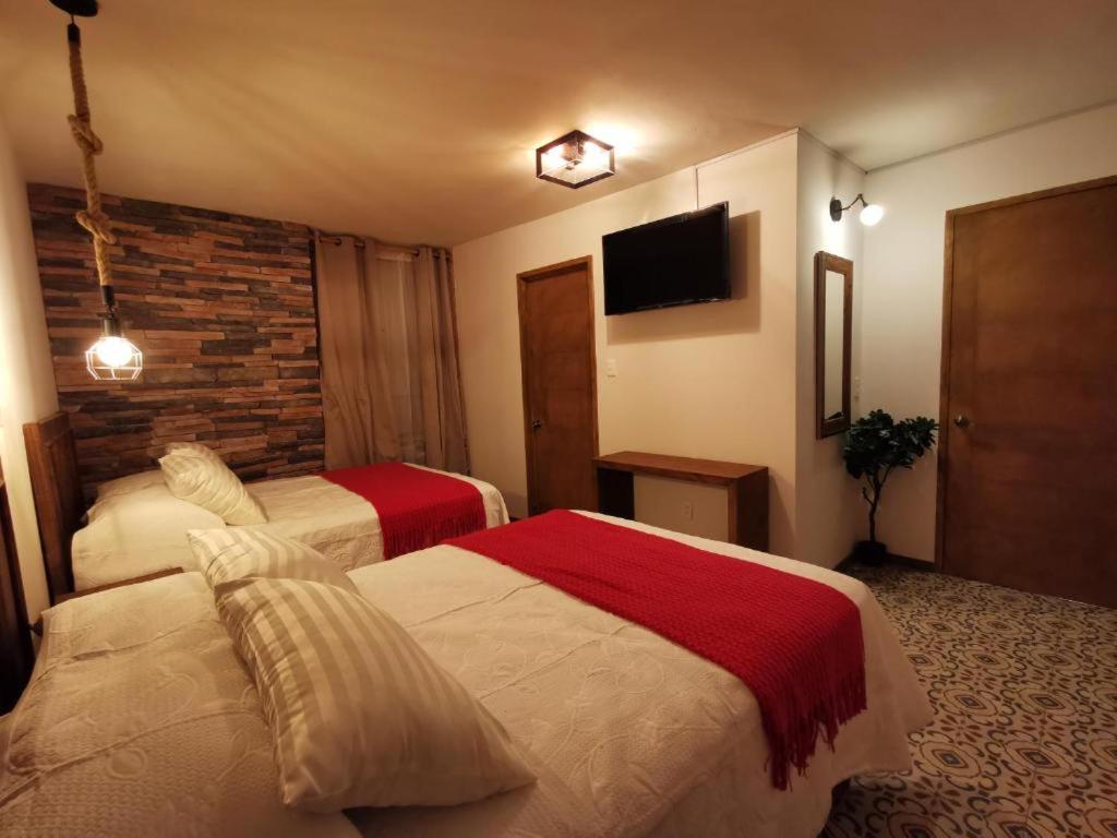 a hotel room with two beds and a brick wall at Hotel Casa Posos in Guanajuato