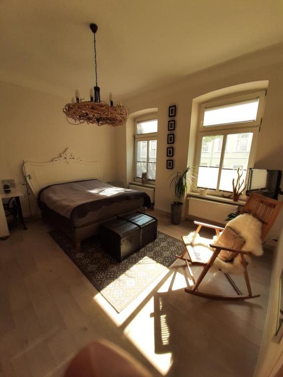 a bedroom with a bed and a chair and windows at City-Apartment 1 in Schwerin