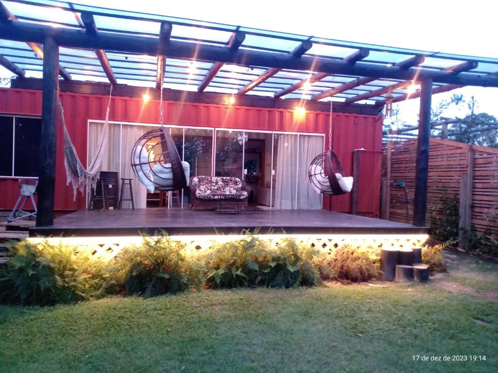 eine Pergola mit einem Sofa und Stühlen auf einer Terrasse in der Unterkunft Casa Container na Praia do Rosa / Ibiraquera in Imbituba