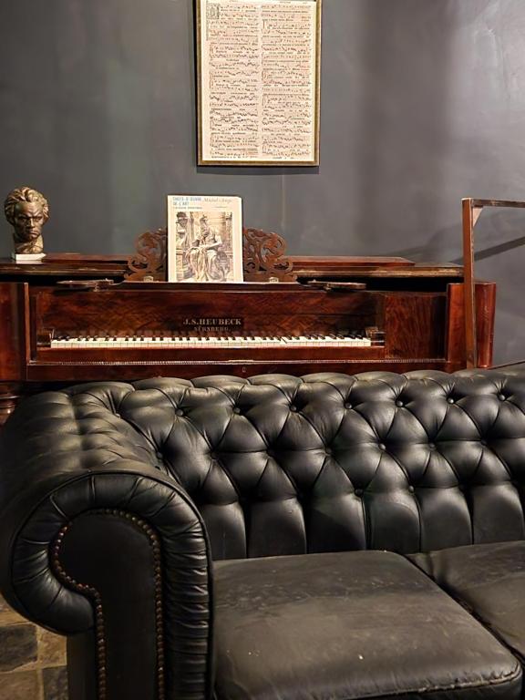 a piano and a leather couch in a living room at Viktoria HOSTEL in Antwerp