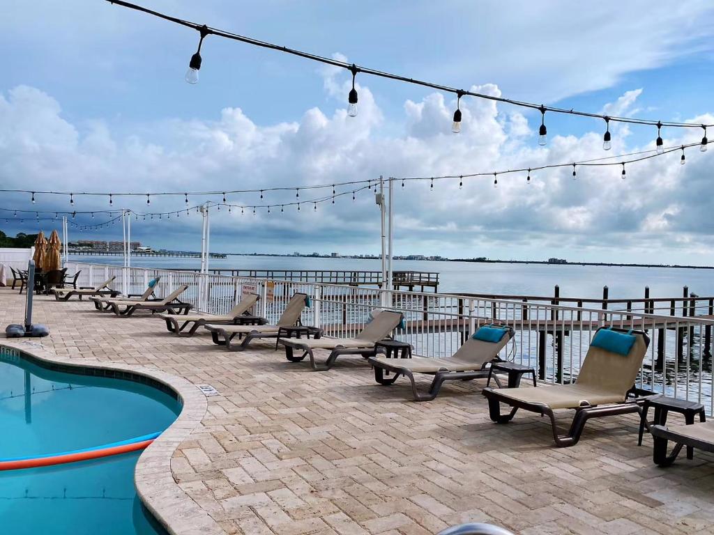 a group of chairs sitting next to a swimming pool at Condo in Waterfront Resort with Balcony Close to Beaches Free Bikes in Dunedin