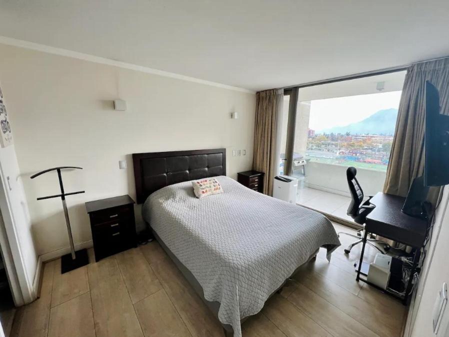 a bedroom with a bed and a desk and a window at Apartamento cerca Mall Alto las Condes in Santiago