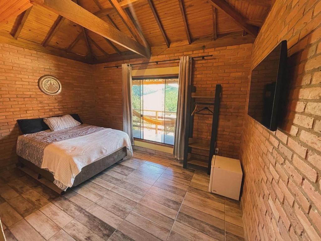 um quarto com uma cama e uma grande janela em Casa Girassol em Conceição da Ibitipoca