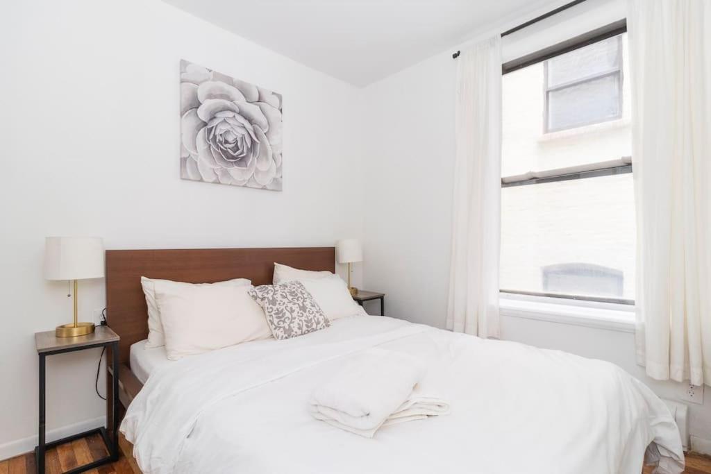 um quarto com uma cama branca e uma janela em 2Bed Bliss by Central Park North em Nova Iorque