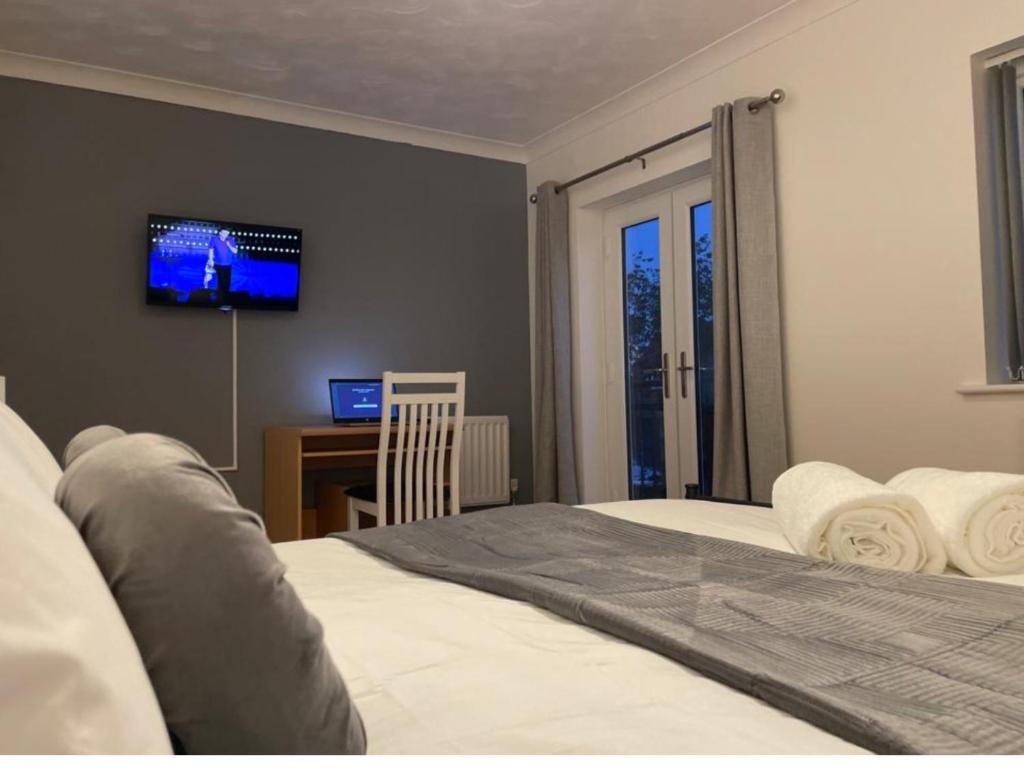a bedroom with a bed with a tv on the wall at Eagle Way Apartment in Peterborough