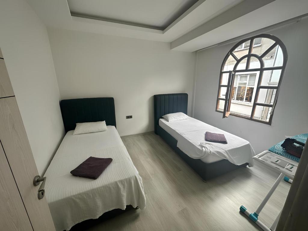 a room with two beds and a window at Long Street Aparments in MEYDAN in Trabzon