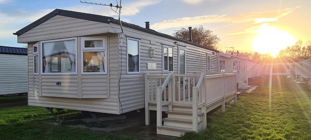 a tiny house sitting on the grass with the sunset at Bewles Caravan in Rhyl