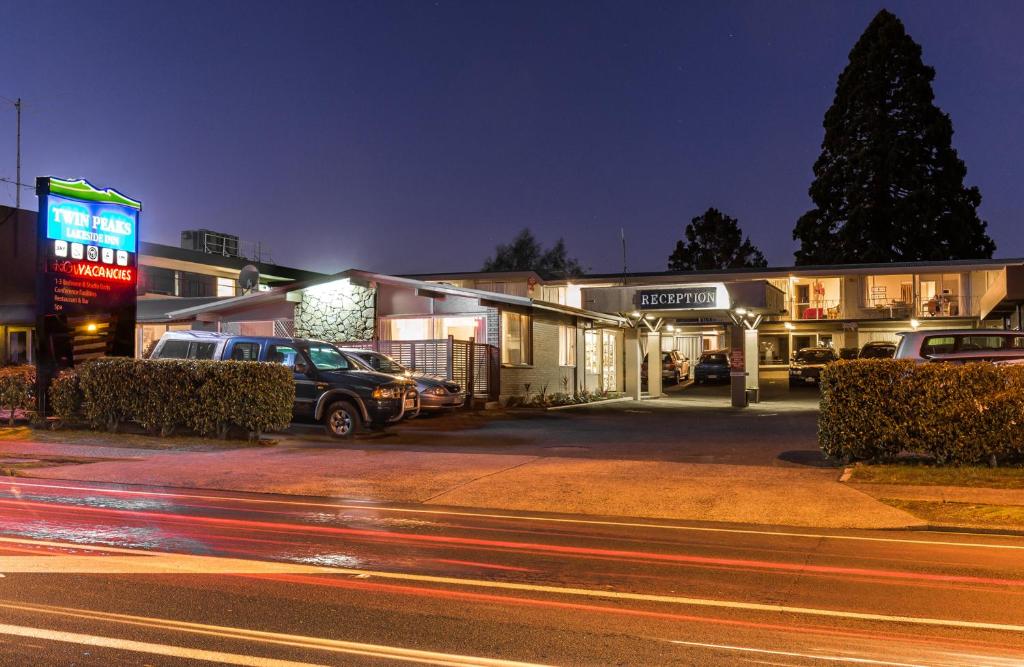 a street with cars parked in front of buildings at night at Twin Peaks Lakeside Inn in Taupo