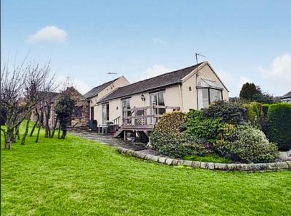 a large house with a green lawn in front of it at Derbyshire Holiday Cottages in Holmesfield