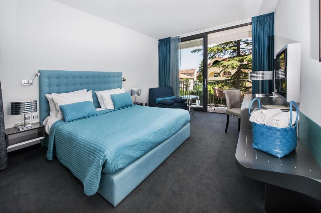 sypialnia z niebieskim łóżkiem i balkonem w obiekcie Hotel Arupinum w Rovinj