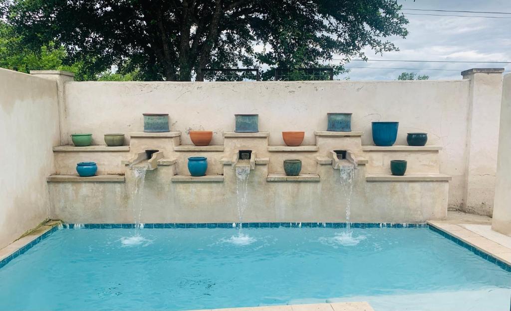 a swimming pool with a fountain with pots on a wall at The Gardens of Barons Creek Unit B in Fredericksburg