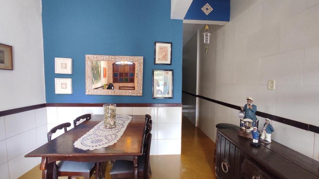 une salle à manger avec une table et un mur bleu dans l'établissement Casa da felicidade praia do forte 2 quartos, à Itaparica Town