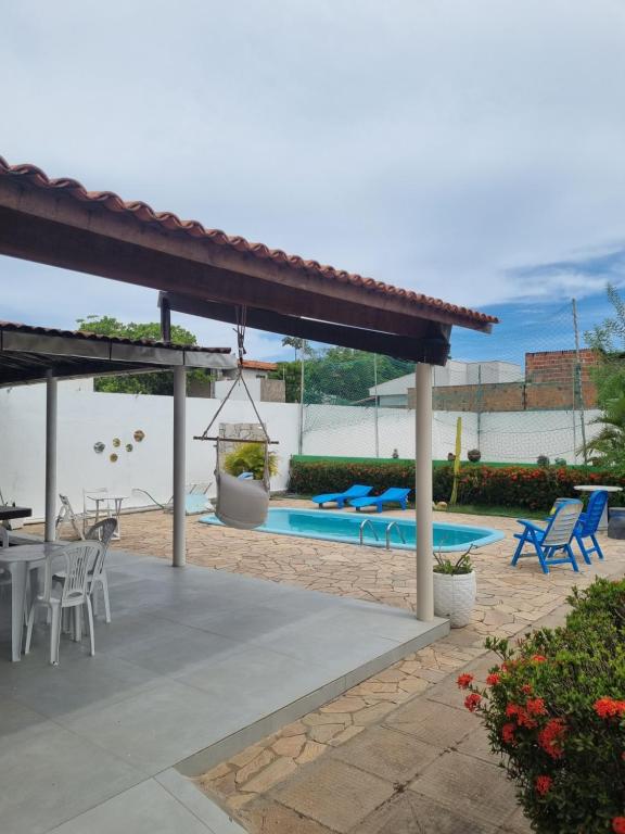 a patio with a table and chairs and a swimming pool at Casa de Praia - Francês/Marechal Deodoro in Marechal Deodoro