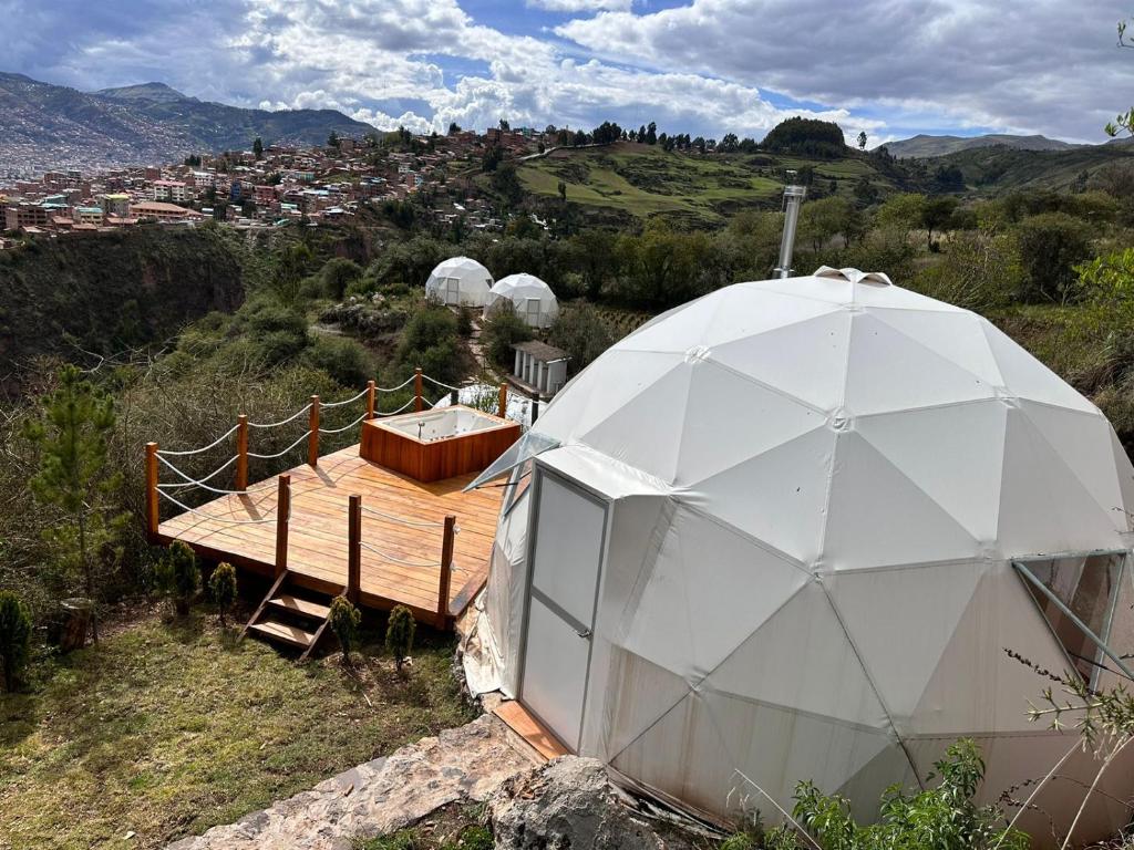 un observatoire de dôme géodésique avec une terrasse en bois et un bâtiment dans l'établissement Sky Lodge Domes Cusco, à Cusco