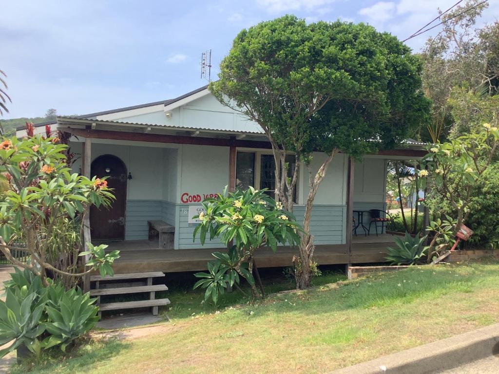 a small blue house with a porch and trees at Good Vibes, 18 East Street in Crescent Head