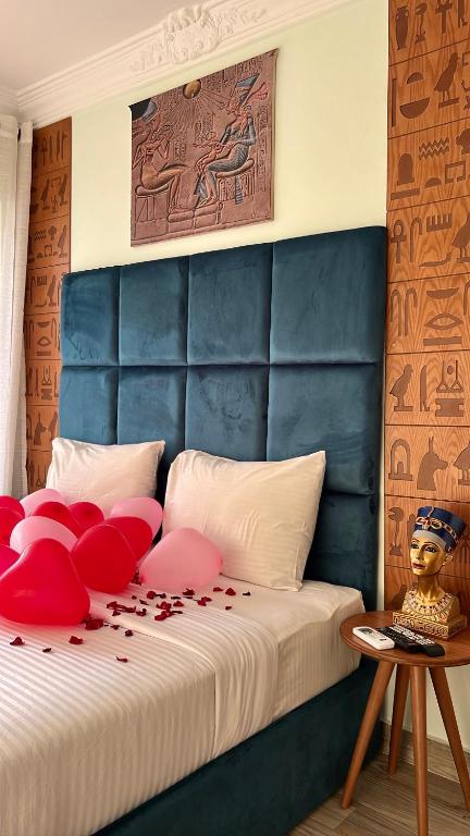 a bedroom with a bed with a blue headboard and red pillows at Jimmy Pyramids Hotel in Cairo