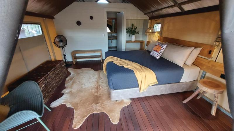 1 dormitorio con 1 cama y suelo de madera en Bell Gorge Wilderness Lodge, en King Leopold Ranges