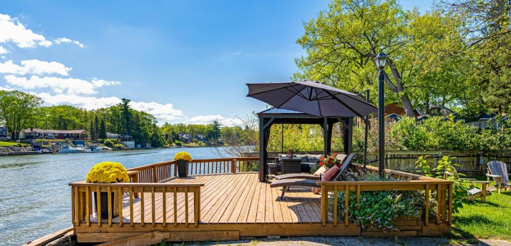 a wooden deck with a gazebo and an umbrella at Charming riverside cottage, walk to beach in Wasaga Beach