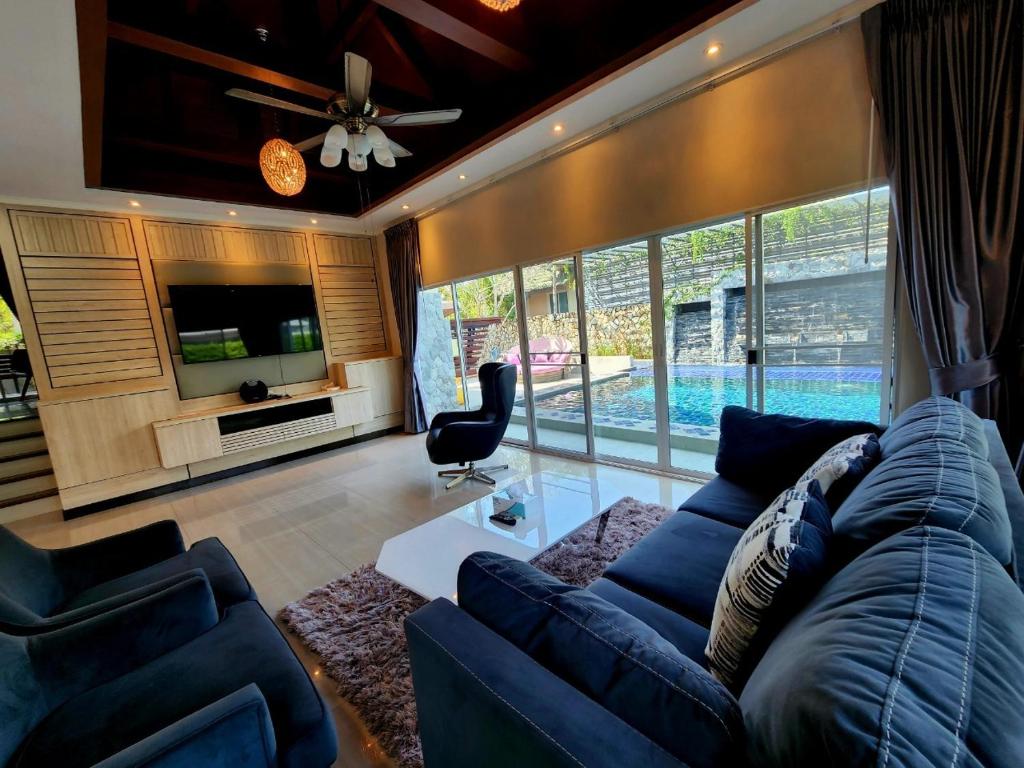 a living room with a blue couch and a tv at I am pool villa Pattaya no14 in Ban Nong Phlap
