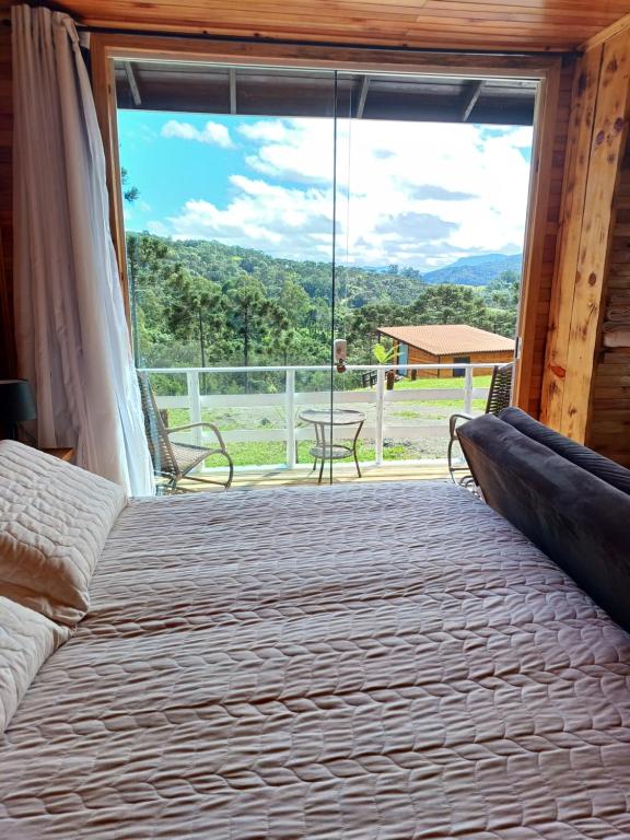 a bedroom with a bed and a large window at Recanto do Ipê cabana 01 in Urubici