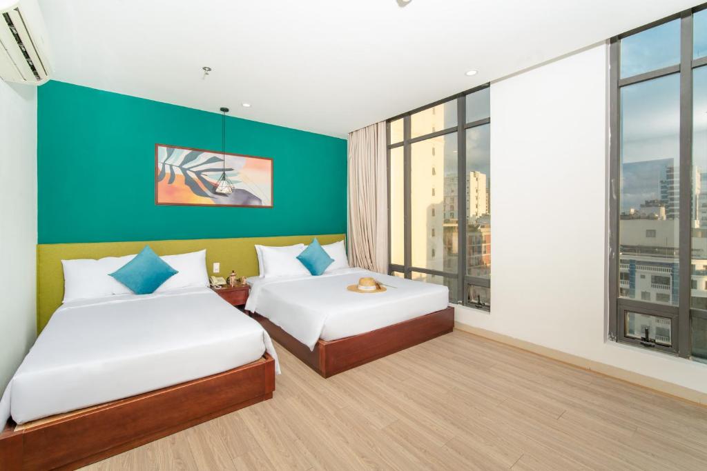 2 Betten in einem Zimmer mit einem großen Fenster in der Unterkunft May Beach Hotel in Đà Nẵng