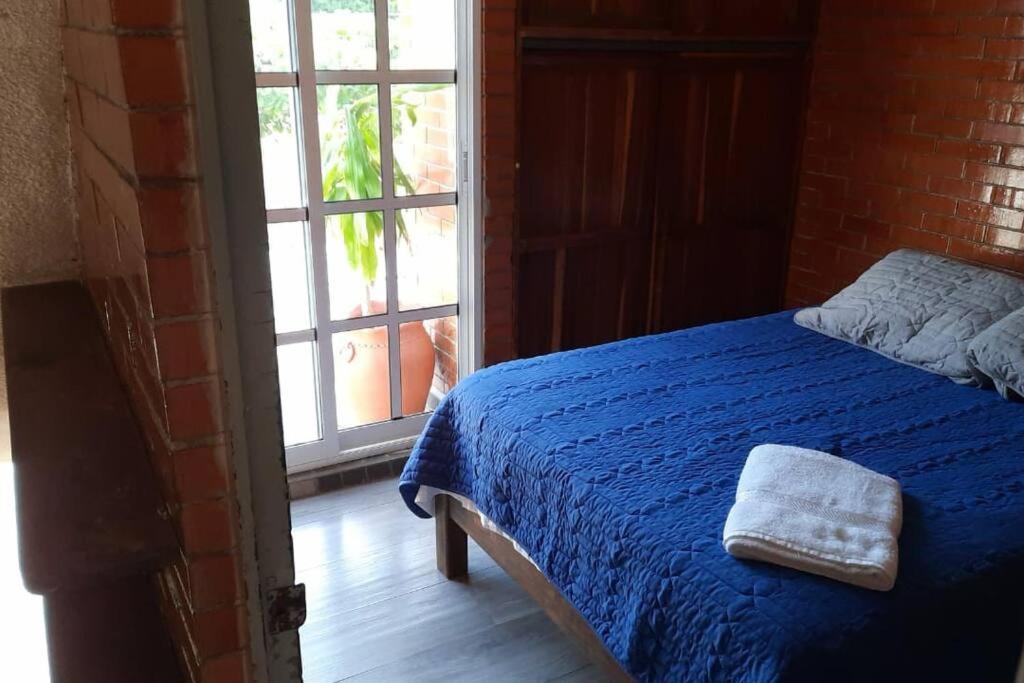 1 dormitorio con 1 cama con manta azul y ventana en Loft guelaguetza A, en Santa Cruz Huatulco