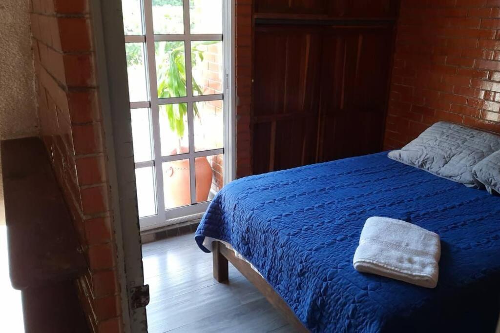 Un dormitorio con una cama con una manta azul y una ventana. en Loft guelaguetza A, en Santa Cruz Huatulco