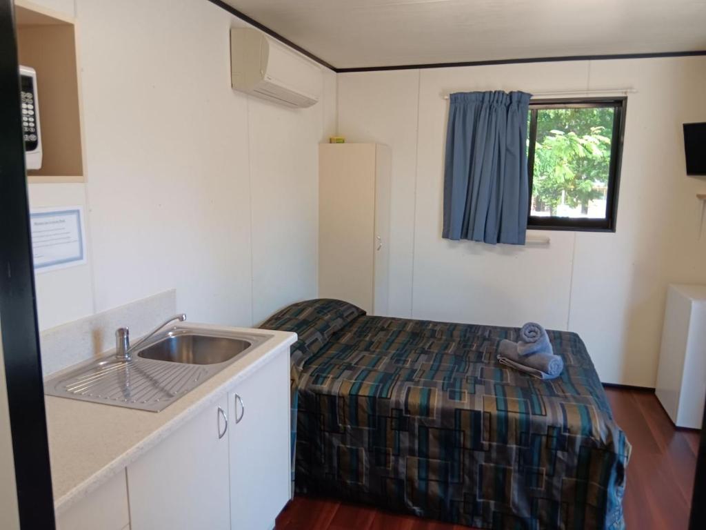 a small room with a sink and a bed in it at Mt Isa Caravan Park in Mount Isa