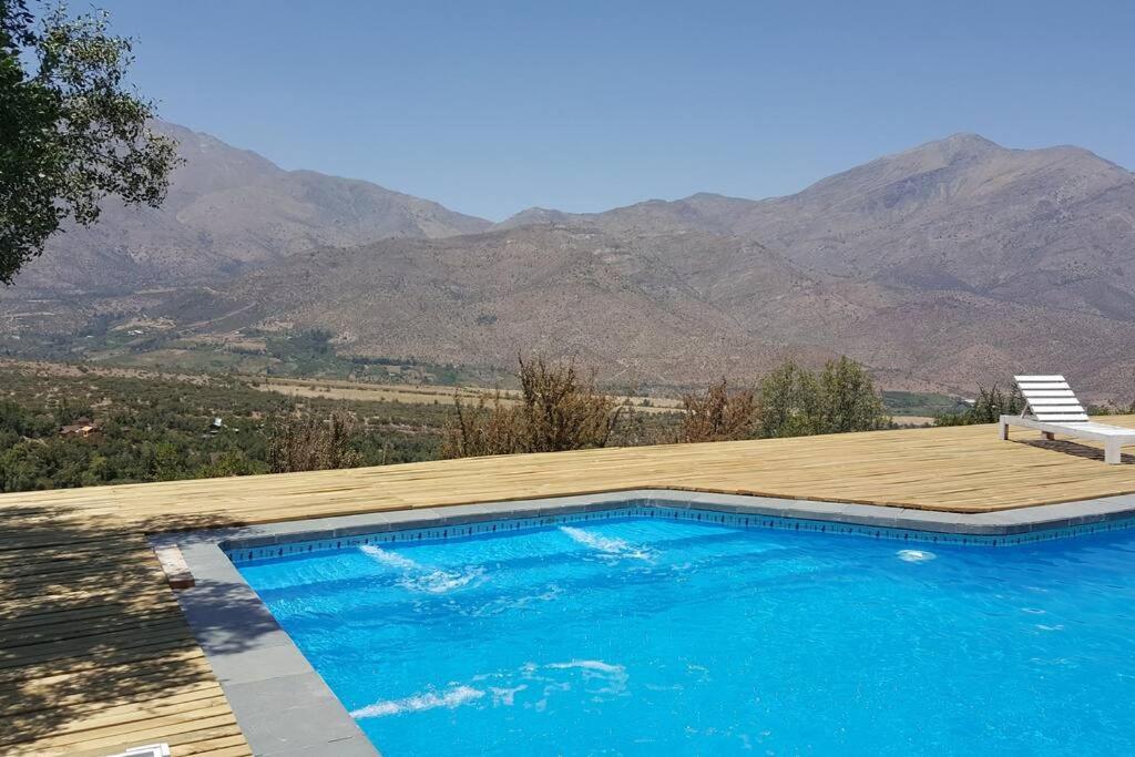 a swimming pool with a deck and mountains in the background at Refugio cordillerano, quincho y piscina in San Francisco