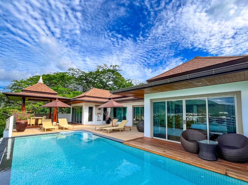 a swimming pool with chairs and a house at Villa Tantawan Resort - Private Pool Villas in Kamala Beach