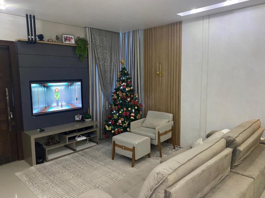 a living room with a christmas tree and a television at Casa com piscina em itapema in Itapema