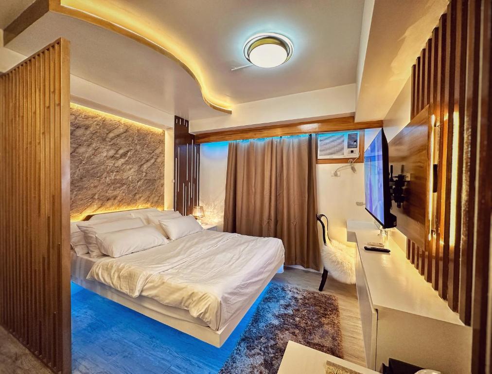 a bedroom with a bed and a desk and a television at RFR Condo Suites in Bacolod