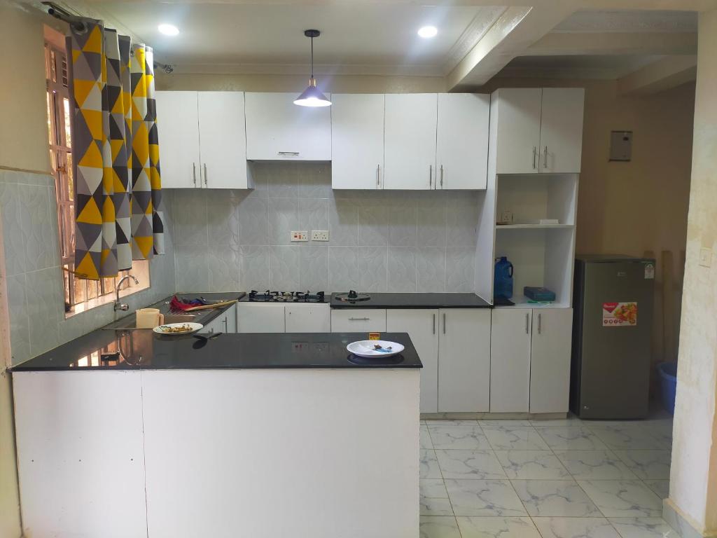 een keuken met witte kasten en een zwart aanrecht bij Golden Home in Maseno