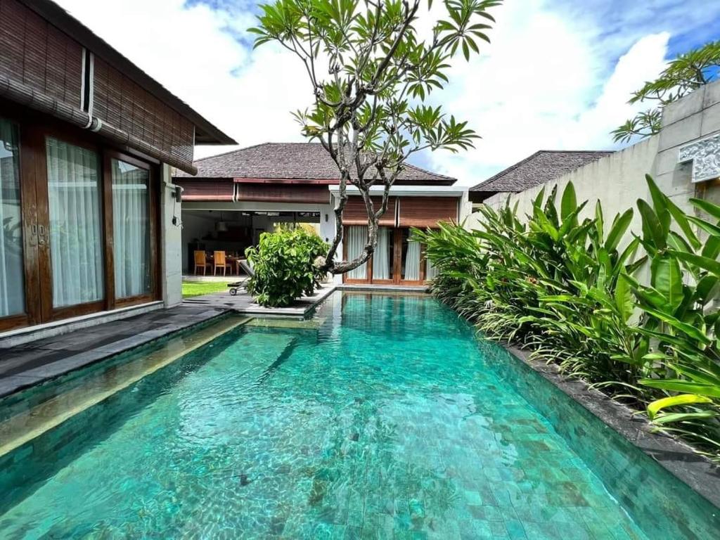 a swimming pool in front of a house at Pradha Villas Seminyak in Seminyak