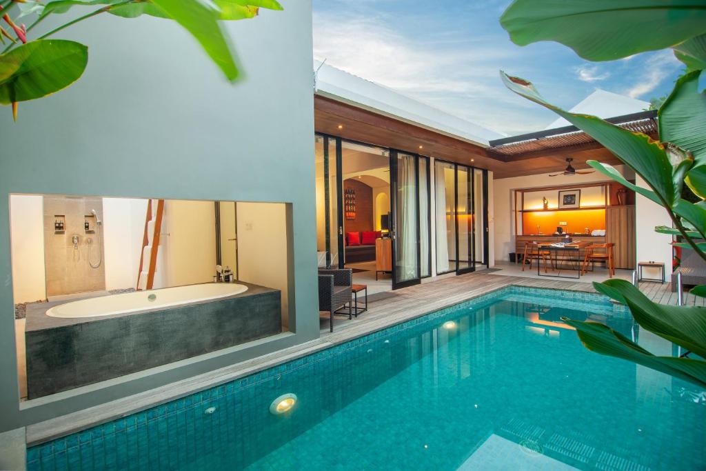 a house with a swimming pool and a tub at Abia Villas in Legian