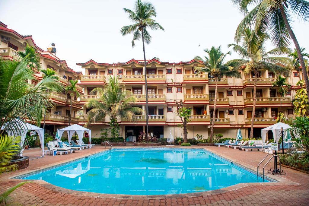 a resort with a large swimming pool in front of a building at CherryStay Holiday Resort -Candolim Beach in Candolim